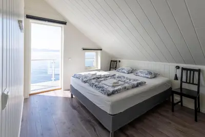 a bedroom with a bed with a view of the ocean at Hjellup Fjordbo in Leksvik