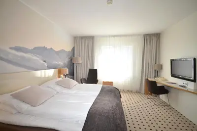 a hotel room with a bed and a flat screen tv at Grand Hotel - by Classic Norway Hotels in Åndalsnes