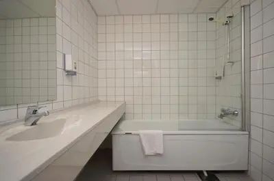a bathroom with a tub and a sink and a mirror at Grand Hotel - by Classic Norway Hotels in Åndalsnes