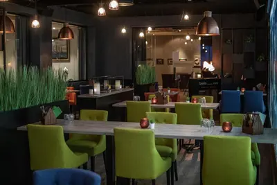 a dining room with tables and green chairs at Grand Hotel - by Classic Norway Hotels in Åndalsnes