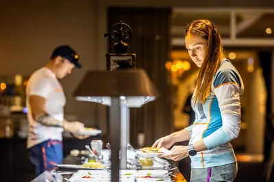 a man and a woman preparing food at a buffet at Grand Hotel - by Classic Norway Hotels in Åndalsnes