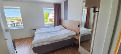 a small room with a bed and a mirror at Systra Hotel Søvik in Syvik