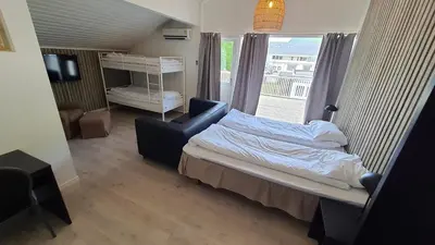 a bedroom with a bed and a chair and a window at Systra Hotel Apartments Sjøholt in Sjøholt