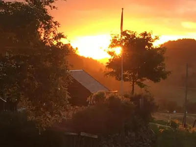 a sunset over a barn with the sun setting at Skjerping gård in Lonevåg