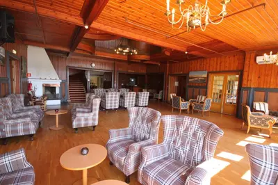 a living room with chairs and tables and a chandelier at Sauda Fjordhotell in Saudasjøen