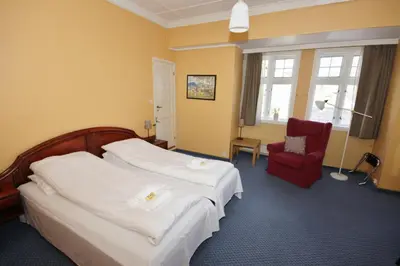 a hotel room with two beds and a red chair at Sauda Fjordhotell in Saudasjøen