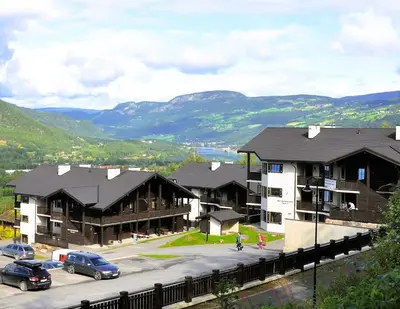 a group of buildings with cars parked in a parking lot at Alpin Apartments Sørlia in Hafjell