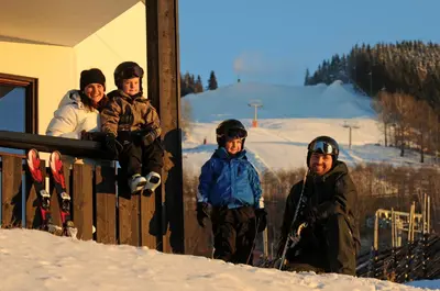 a group of people standing on a porch in the snow at Alpin Apartments Solsiden in Hafjell