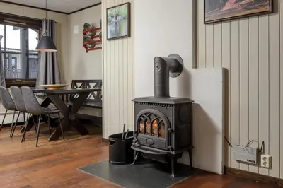 a wood stove in a living room with a table at Alpin Apartments Solsiden in Hafjell