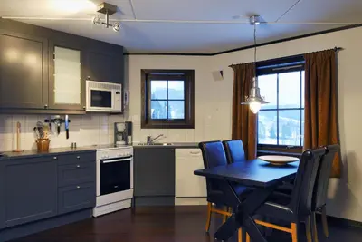 a kitchen with a table and a dining room at Alpin Apartments Solsiden in Hafjell