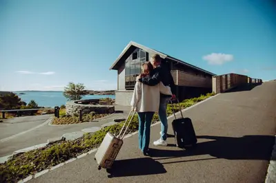 a man and woman walking down a sidewalk with their luggage at Panorama Hotell & Resort in Steinsland