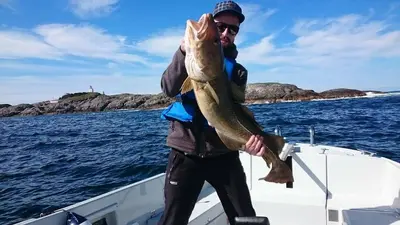 a man holding a large fish on a boat at Panorama Hotell & Resort in Steinsland