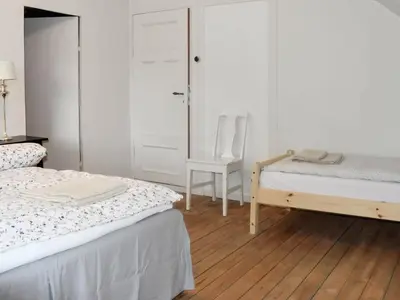 a white room with two beds and a chair at 8 person holiday home in Masfjordnes-By Traum in Masfjorden