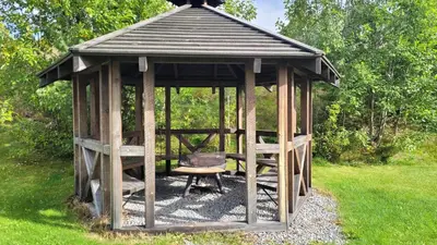 a wooden gazebo with a grill in the grass at Øen Turistsenter Cottages in Geilo