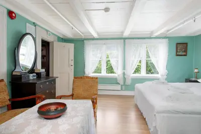 a bedroom with a bed and a table and a mirror at Jaunsen Gjestgjevarstad in Granvin