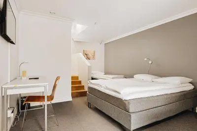 a bedroom with a bed and a desk and a table at Klosterhagen Hotel in Bergen