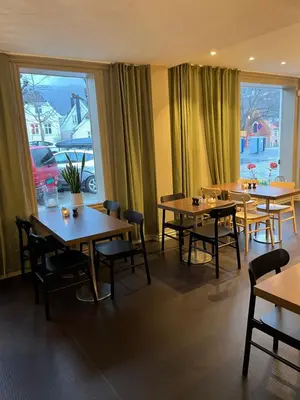 a restaurant with tables and chairs and a large window at Klosterhagen Hotel in Bergen