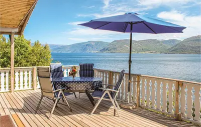 a table and chairs on a deck with an umbrella at 3 Bedroom Cozy Home In Lavik in Lavik