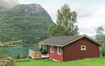 a small red house with a deck next to a lake at Stunning Home In Olden With Kitchen in Olden