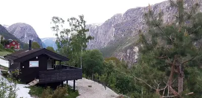 a small black building on a hill with mountains at Stalheim Fjord og Fjellhytter in Stalheim