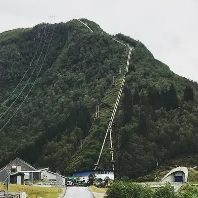 a mountain with a suspension bridge over a road at Øren Hotel in Høyanger