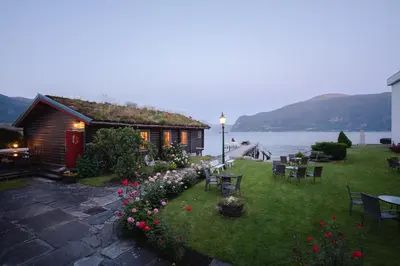 a house with a yard with chairs and flowers at Leikanger Fjordhotel - Unike Hoteller in Leikanger