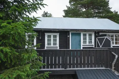 a tiny house with a porch and a blue door at Lesjaskogsvatnet Camping in Lesjaskog