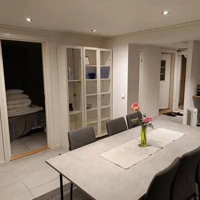 a dining room with a table with a vase of flowers at Malvik, Hundhamaren, Trondheim in Malvik