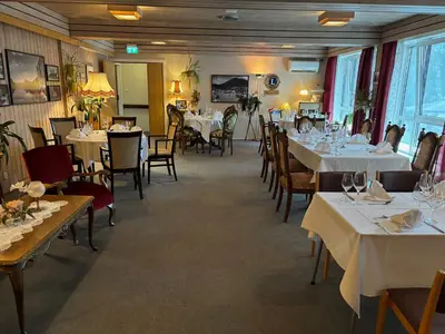 a dining room with tables and chairs with white tablecloths at Eikum Hotel in Hafslo
