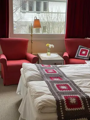 a bedroom with two chairs and a bed with a blanket at Eikum Hotel in Hafslo
