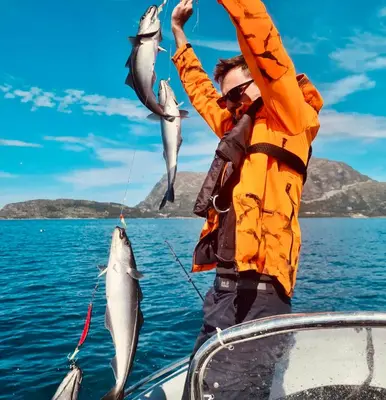 a man on a boat holding two fish in the air at Awesome Fishing, Boating and Nature Experience at Fiskesenter Birkeland in Rekdal