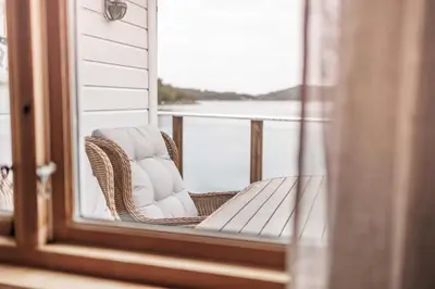 a wicker chair on a porch with a view of the water at Eastside Cottages in Bømlo