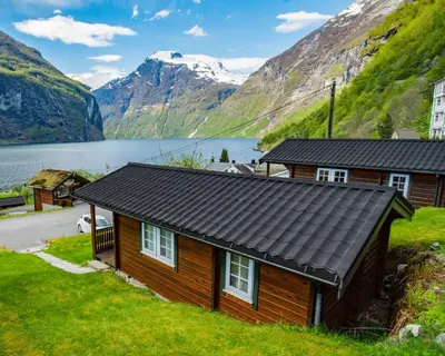 a cabin with a view of a lake and mountains at Grande Hytteutleige og Camping in Geiranger