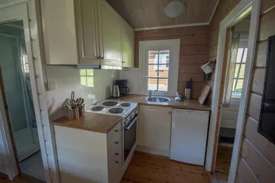 a small kitchen with a stove and a sink at Grande Hytteutleige og Camping in Geiranger