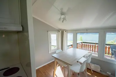 a dining room with a table and chairs and a balcony at Grande Hytteutleige og Camping in Geiranger