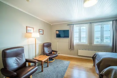a room with a bed and two chairs and a tv at Finnøy Bryggehotell - by Classic Norway Hotels in Finnøy