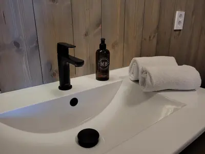 a bathroom sink with a bottle of wine on it at Ona Havstuer - by Classic Norway Hotels in Ona