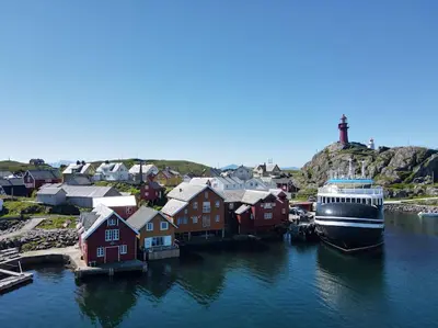 a cruise ship docked in a harbor next to houses at Ona Havstuer - by Classic Norway Hotels in Ona