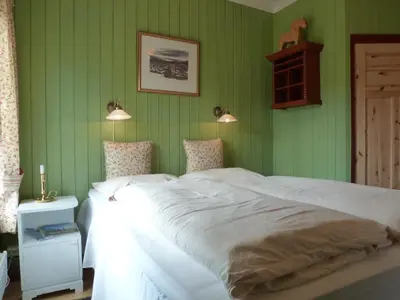 a bedroom with green walls and a large white bed at Kvebergsøya Gard in Grimsbu