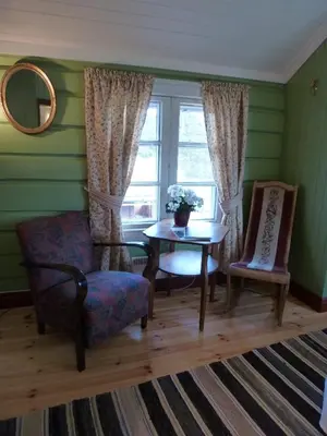 a living room with a table and chairs and a window at Kvebergsøya Gard in Grimsbu