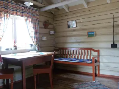 a room with a table and a bench in a log cabin at Kvebergsøya Gard in Grimsbu