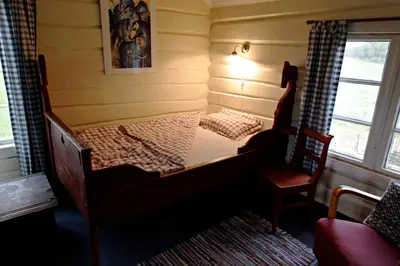 a small bedroom with a bed and a chair at Kvebergsøya Gard in Grimsbu