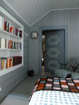 a bedroom with a bed and a book shelf at Kvebergsøya Gard in Grimsbu