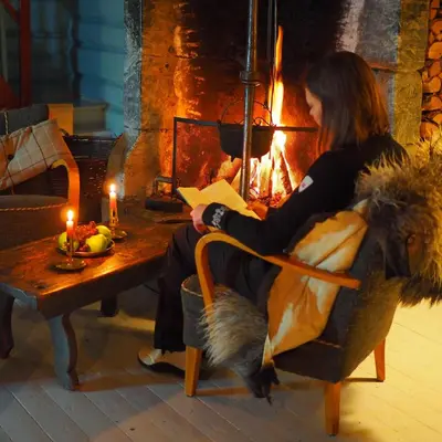 a woman sitting in a chair in front of a fireplace at Kvebergsøya Gard in Grimsbu