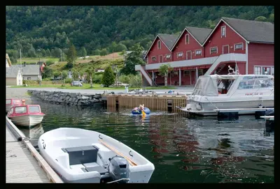 a person in a raft in the water next to a boat at Grandane Feriehus in Stongfjorden