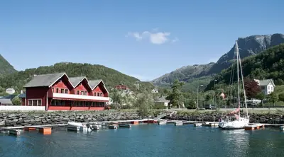 a marina with a red building and boats in the water at Grandane Feriehus in Stongfjorden