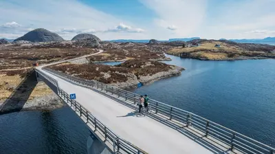 a man walking on a bridge over a body of water at Værlandet Havhotell in Hamna