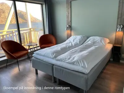 a bed in a room with two chairs and a window at Værlandet Havhotell in Hamna