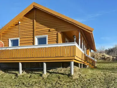 a wooden house with a porch on a field at 6 person holiday home in Aukra in Aukra