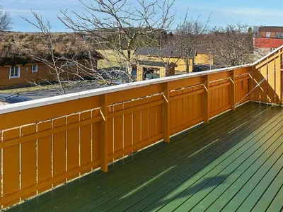 a wooden deck with a yellow fence on it at 6 person holiday home in Aukra in Aukra